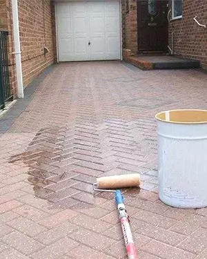 applying sealant on a paved driveway